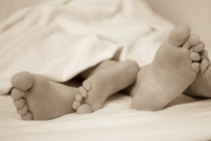 two sets of feet in a bed