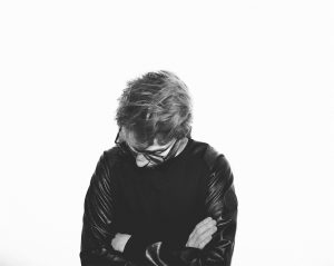 black and white picture of a man with his hands crossed and looking down