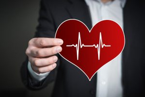 person in a suit holding a heart with a heartbeat in it