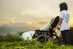 sick person in a wheelchair being pushed by a young female