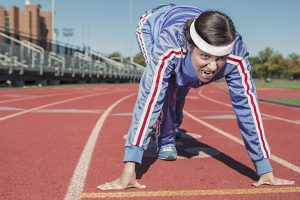 woman in a blue track suit positioned down to race on a track.