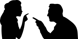 silhouette of a man and woman pointing fingers at each other. 