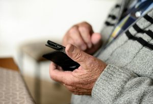 older looking hands holding a cell phone