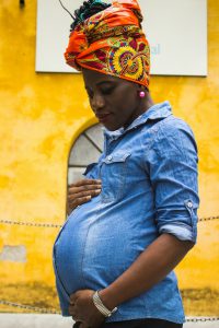 african american woman in a denim shirt holding her pregnant belly