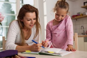 woman and a little girl looking down at a piece of paper on a table