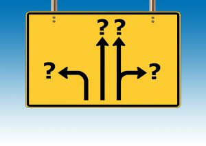 yellow sign with arrows and question marks at the end of the arrows