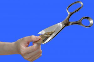 scissors cutting a credit card that is being held by a hand