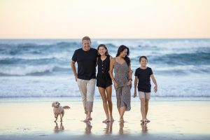 a family of four walking on the beach smiling