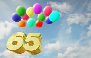 the numbers 65 in gold floating in the air with balloons tied to it