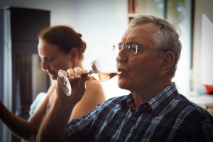 man drinking a glass of wine next to a woman
