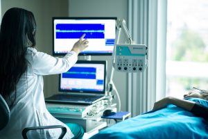 person in a hospital bed with a dr pointing at a monitor screen