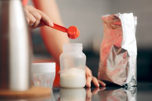 hands pouring baby formula into a baby bottle