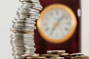 coins stacked up with a clock blurred out in the background