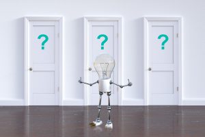light bulb standing in front of 3 white doors with blue question marks on them