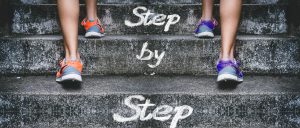 two sets of feet going up stairs with the words "step by step" on it