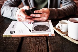 person sitting at a table with their cell phone in their hands