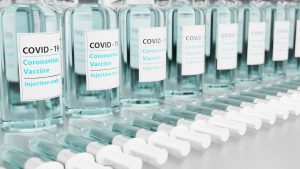 multiple covid vials with needles lined up in front of them