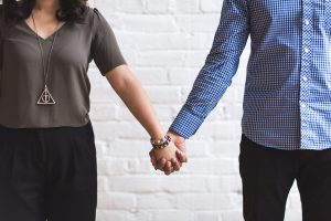 two people standing far apart holding hands