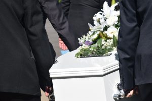 people carrying a white casket with white flowers on it