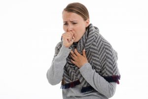 caucasian woman wrapped in a scarf coughing