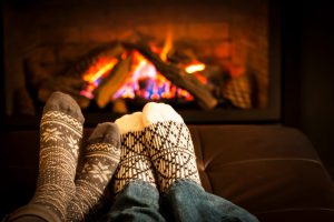 two sets of feet in socks next to each other with a fire in the background