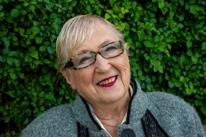 older Caucasian woman with short hair and glasses smiling