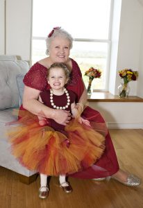 older woman in a red dress hugging a little girl in a dress