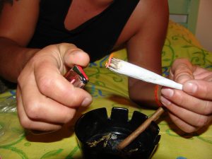 hand holding a white joint with the other hand lighting it up with a lighter