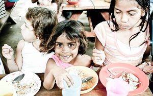 yound children smiling with a plate of food in their hands