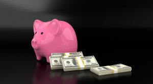pink piggy bank with stacks of money next to it