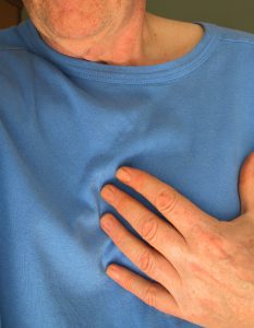 caucasian person with a blue shirt on holding their heart area