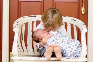 toddler holding a baby and kissing it