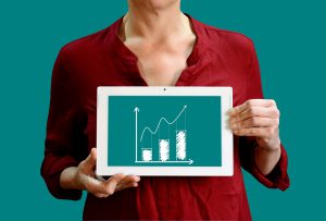 torso of a woman holding a tablet with a bar graph moving upward