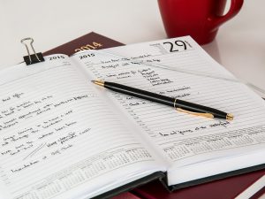 open calendar with a pen on the page and writing on each page