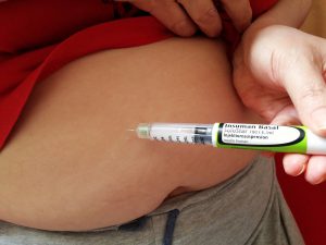a person injecting a shot into the stomach