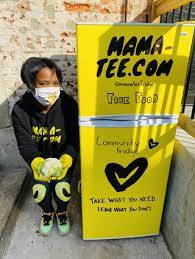 Michelle Nelson squatting next to a mama-tee yellow fridge