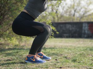 body of a woman doing a squat outdoors