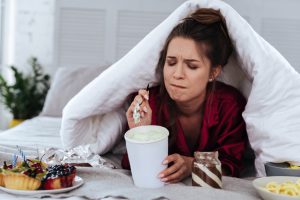 woman stress eating ice cream under the covers