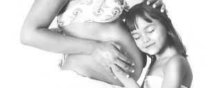 black and white photo of a pregnant woman's belly with a child's head on it while smiling
