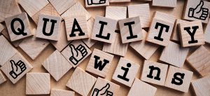 "quality wins" written in scrabble letters with thumbs up around it