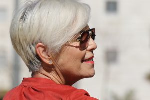 older woman with short gray hair and sunglasses on smiling