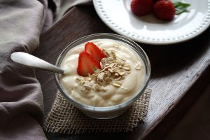 plain yogurt in a cup with strawberries and granola on top