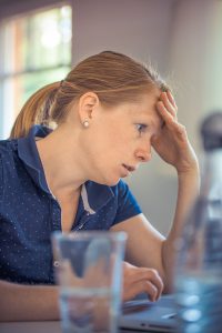 woman looking distressed while looking at a computer screen