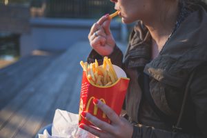 person holding McDonald's fries and eating one