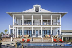bid beach house with pillars and a pool