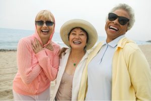 3 older women laughing together on the beach
