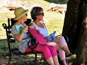 2 older women sitting on a bench outside