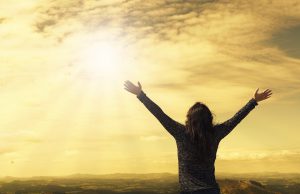 silhouette of a woman raising her arms towards the sun