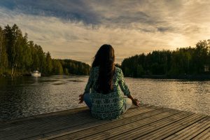 woman sitting at a dock meditating