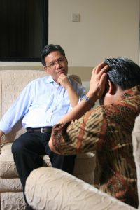 man sitting across from another man with his head in his hands and the other one listening